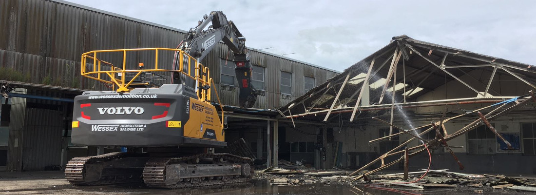 Volvo EC250EL Excavator removing a metal sheet roof